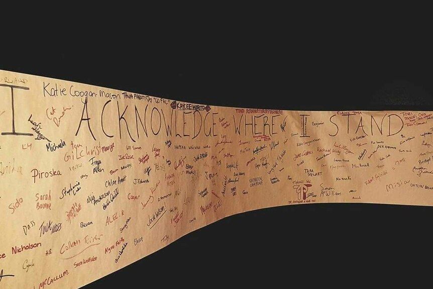 A long piece of butcher's paper with the words I ACKNOWLEDE WHERE I STAND written on it in marker pen, surrounded by signatures.