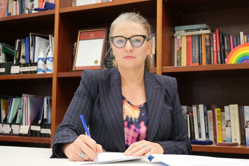 West Australian Senator Louise Pratt sitting behind a desk in her Perth office holding a pen. Taken 15/07/21