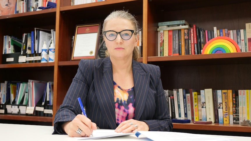 West Australian Senator Louise Pratt sitting behind a desk in her Perth office holding a pen. Taken 15/07/21