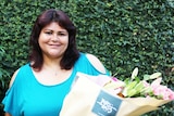 A smiling woman hold a big bunch of flowers.