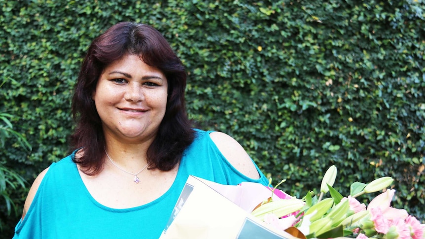 A smiling woman hold a big bunch of flowers.