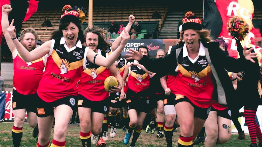 Adelaide musicians run onto the field ahead of a Reclink Community Cup AFL game