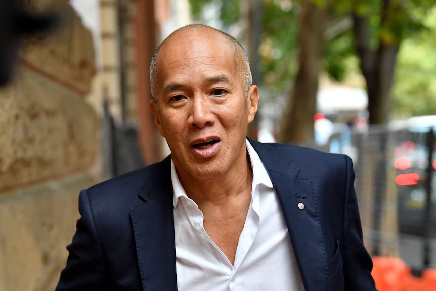 Bald man in dark blue suit walking 