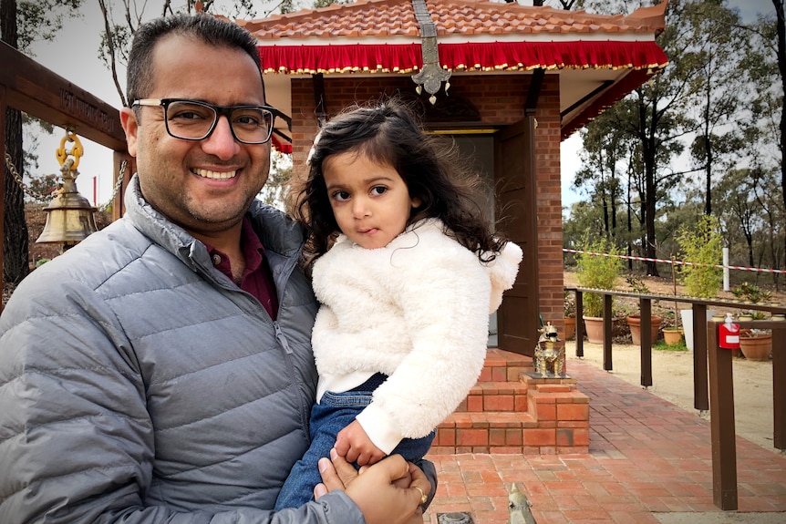 an Indian man and his daughter smile at the camera