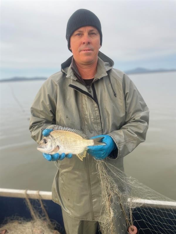 Photo of a man on a boat holding a fish.