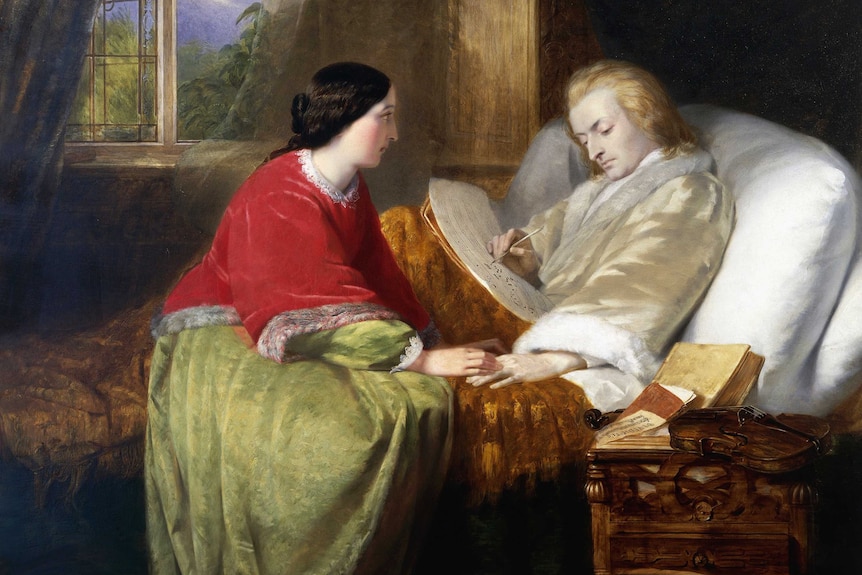 The composer Wolfgang Amadeus Mozart is writing music from his bed, his hand is held by a female companion.