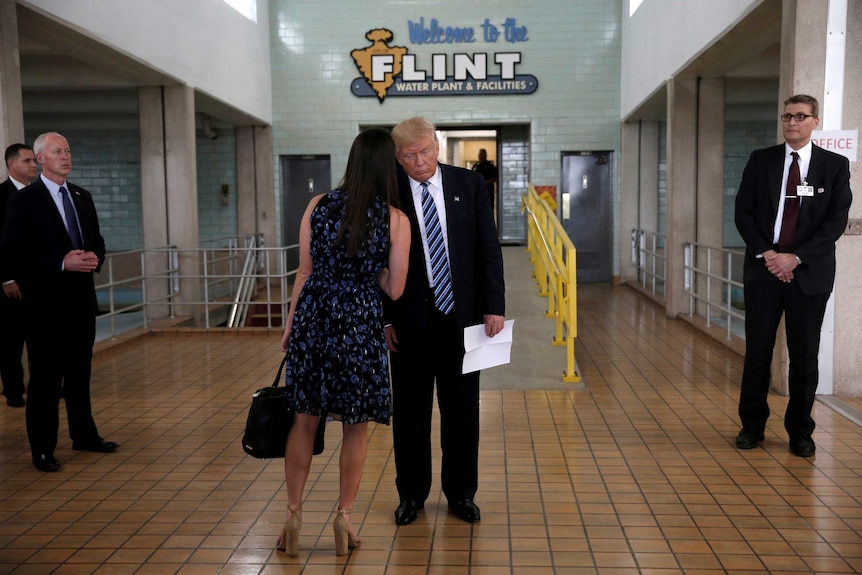 Hope Hicks whispers in Donald Trump's ear.