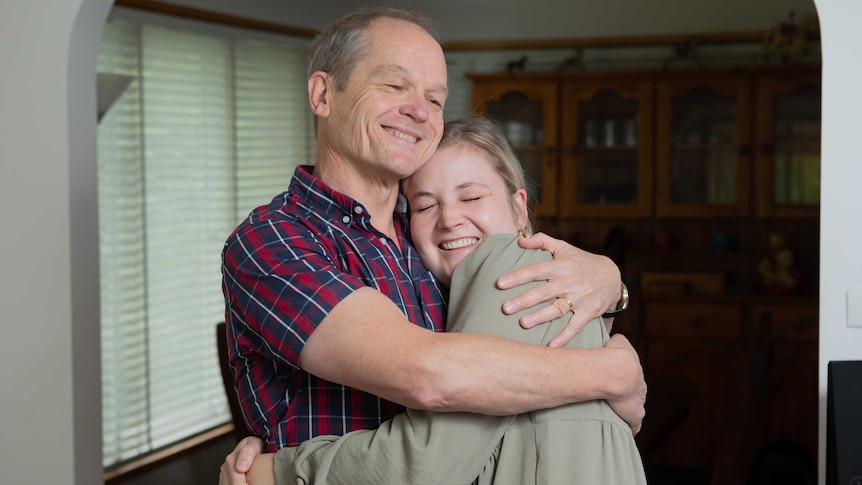 An older man hugs a smiling younger woman.