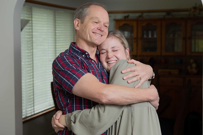 An older man hugs a smiling younger woman.