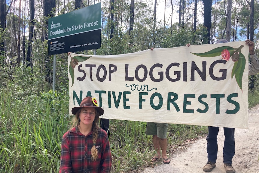 woman with 'stop logging our native forests'behind her