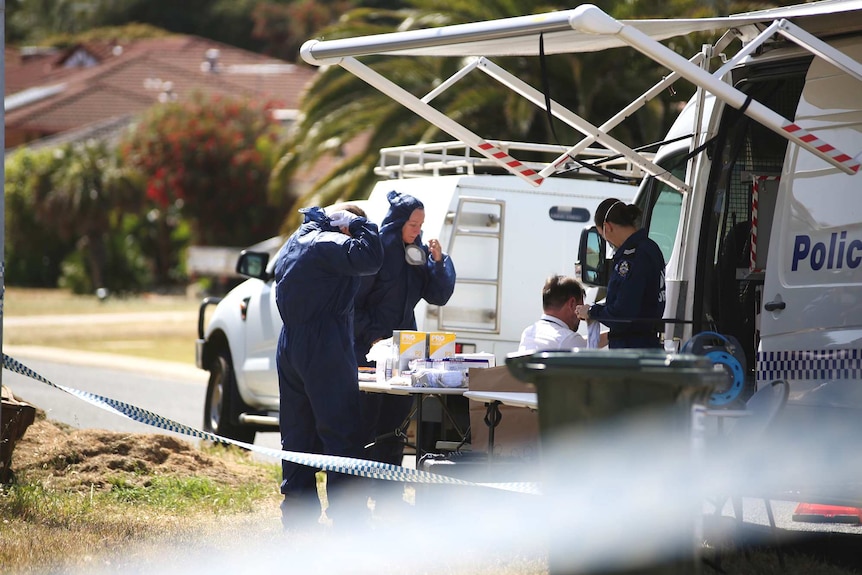 A group of WA Police forensic officers stand around a table near a police command vehicle on a Joondalup street.