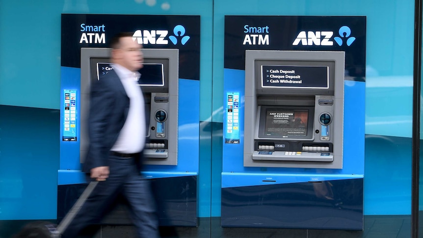 A man in a suit walks passed an unused ATM