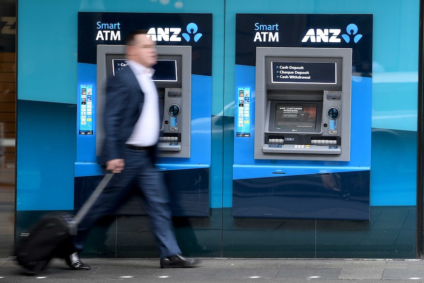 A man in a suit walks passed an unused ATM