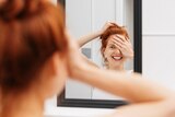 Woman standing in a bathroom smiling in mirror reflection