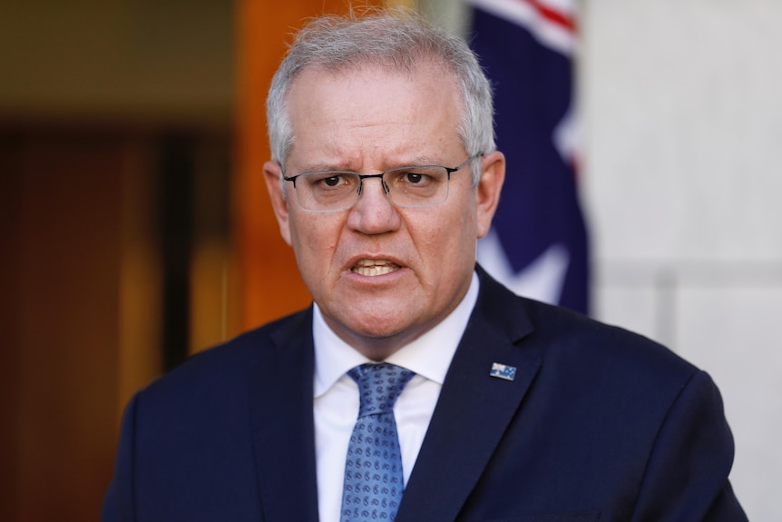 Prime Minister Scott Morrison speaks in front of an Australian flag.