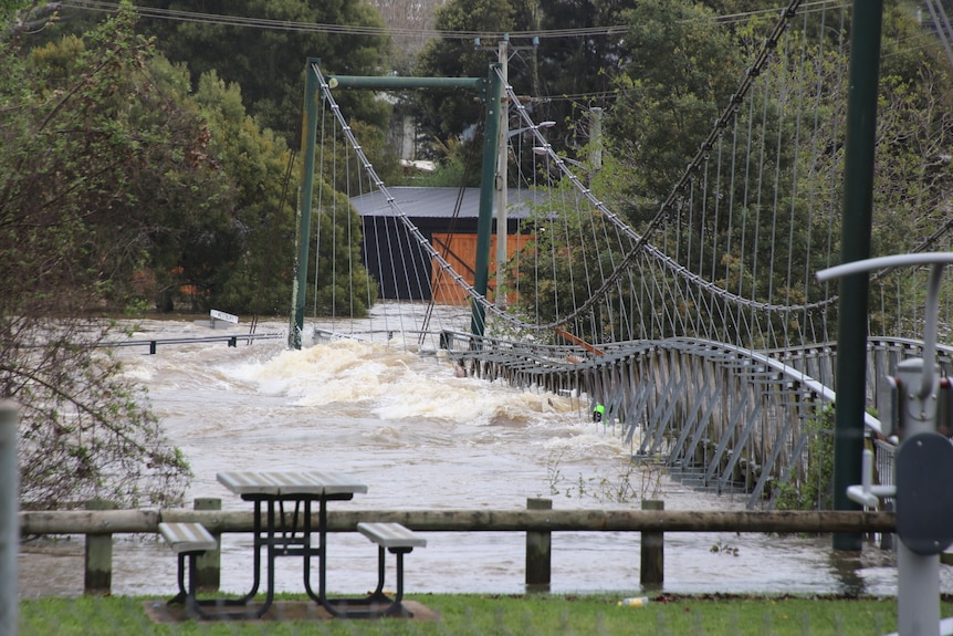 Floodwater smashes into a footbridge over Meander River.