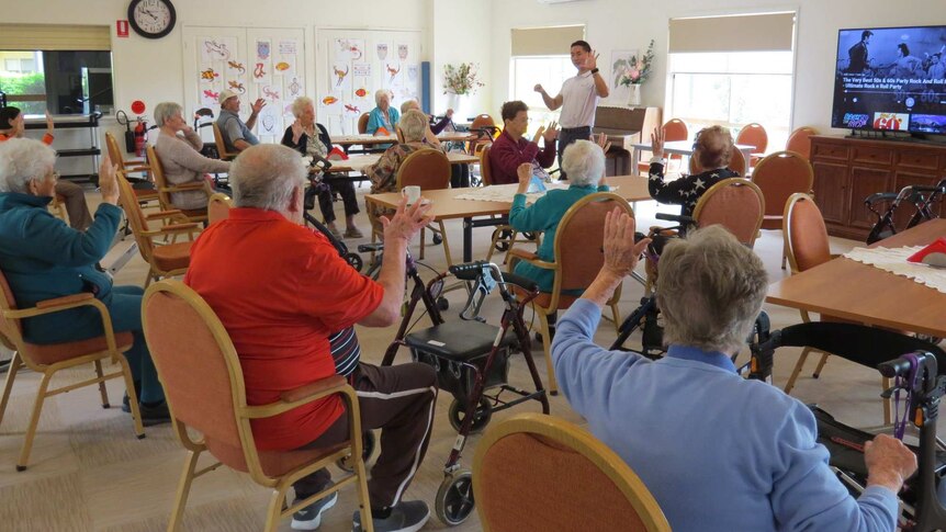 group of aged care residents sitting at tables in a room
