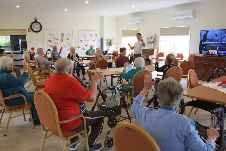 group of aged care residents sitting at tables in a room