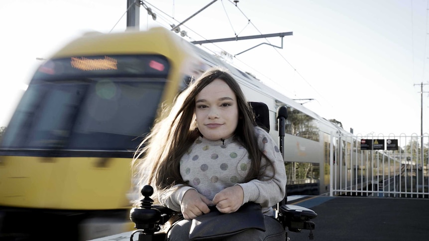 Jacqui Facaris, a 21-year-old woman who uses a wheelchair, waits on a platform as a train arrives