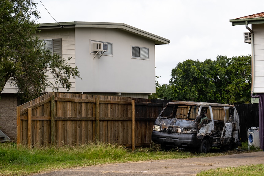 Burnt out wagon in front of house