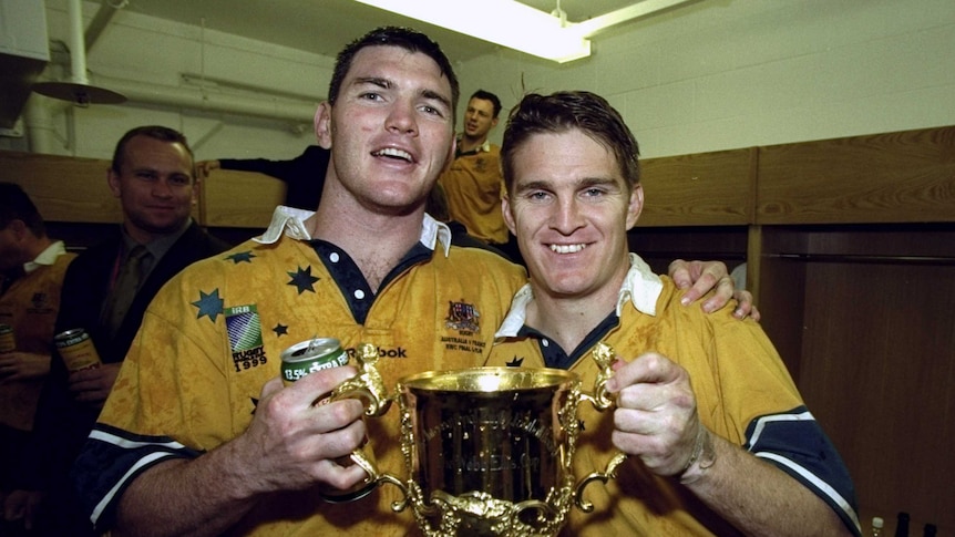 Winners are grinners ... Daniel Herbert (L) and Tim Horan celebrate with the Webb Ellis Cup