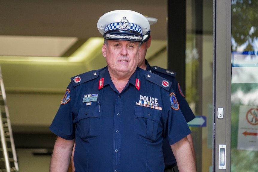 A man in a NT Police uniform walking out the front door of a court house. 