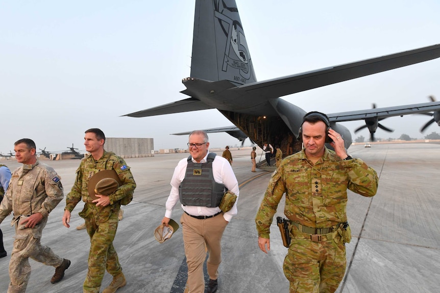 Scott Morrison walks with three soldiers on an airstrip