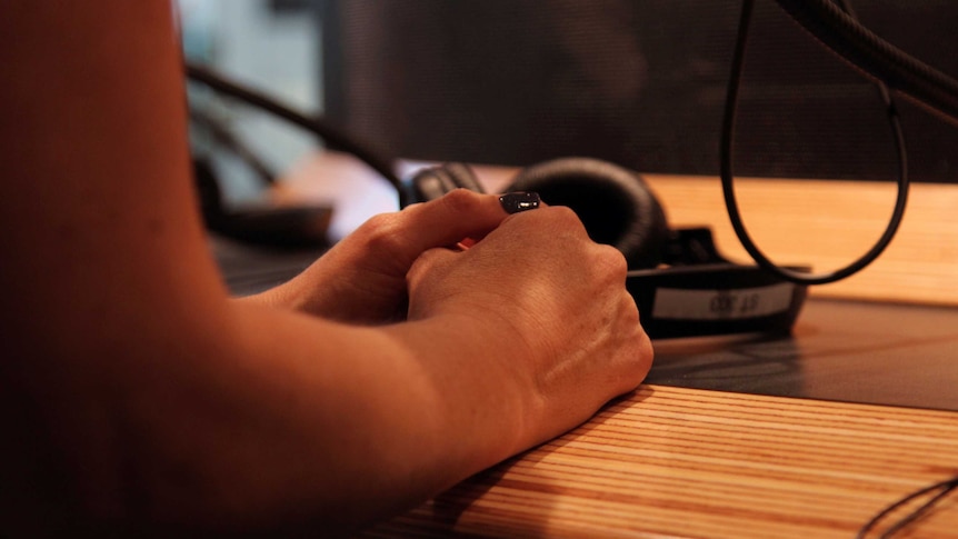 Emily's hands clasped on a desk near a set of headphones.