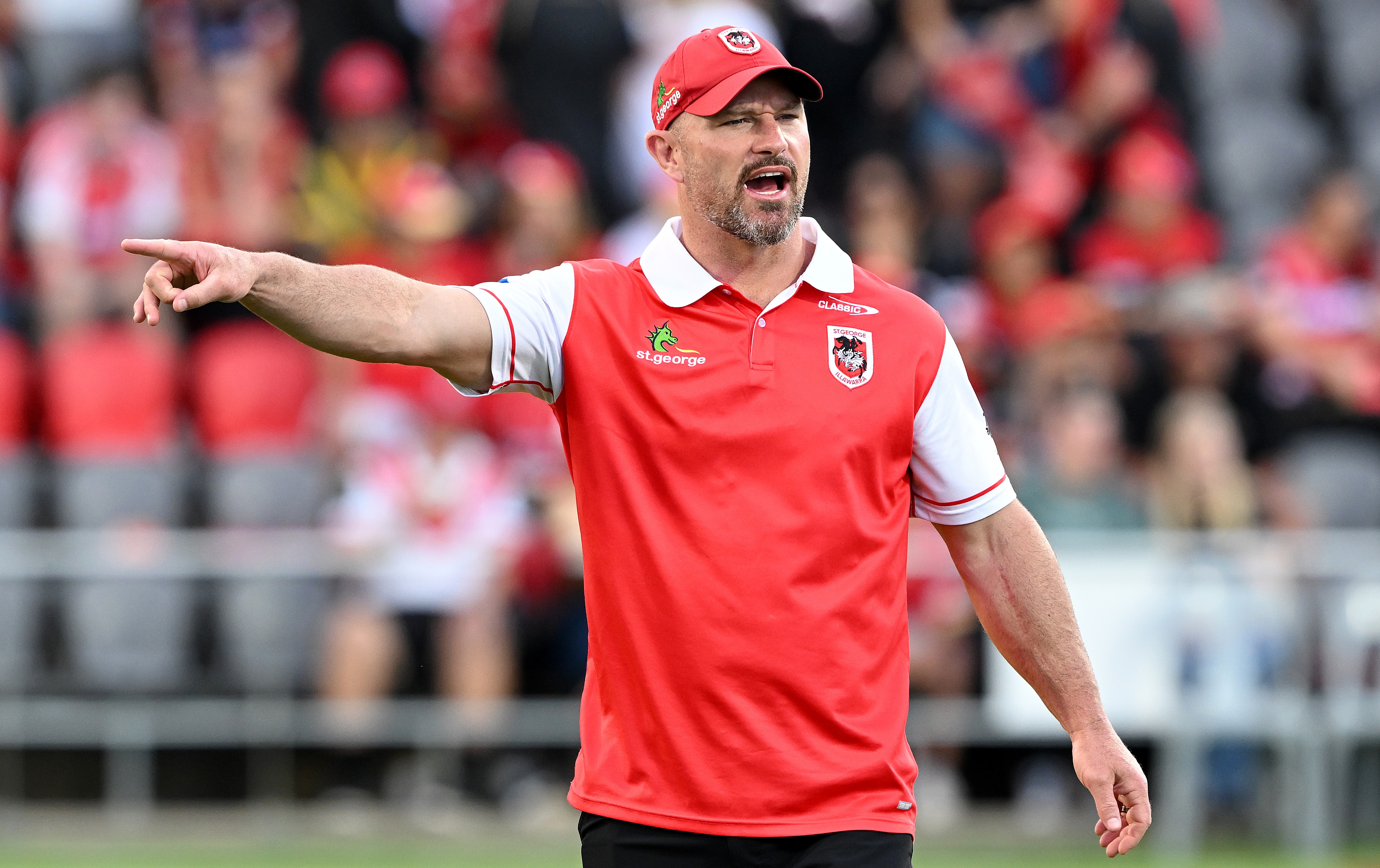 Dean Young points and shouts while wearing St George Illawarra cap and polo shirt.