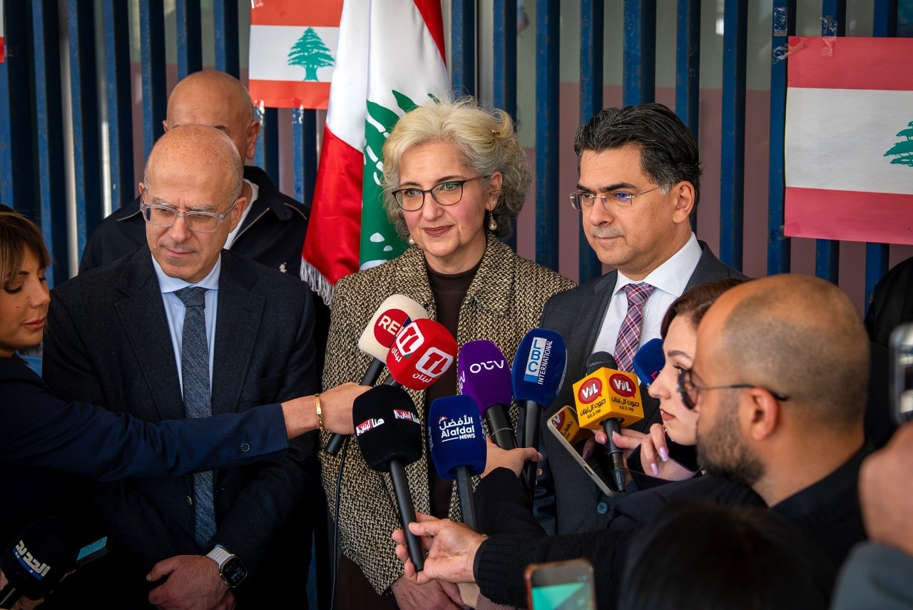 A woman speaking to a large crowd of reporters.