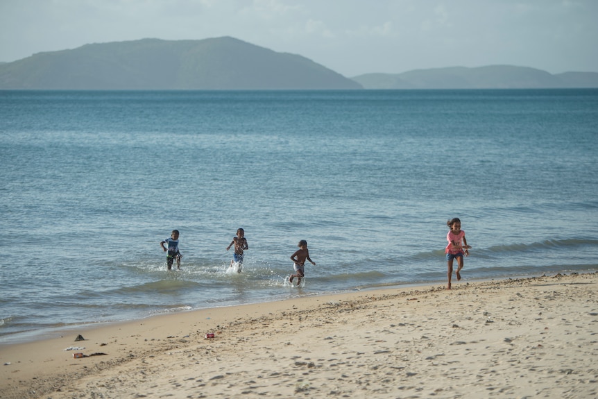 Children running on beach and in ocean.