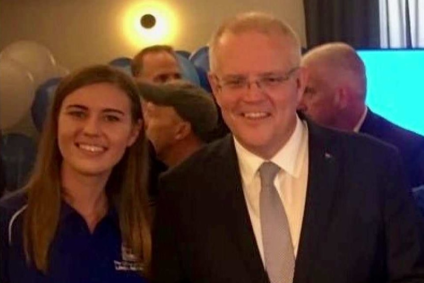 Brittany Higgins, wearing a Liberal Party t-shirt, stands next to Prime Minister Scott Morrison.