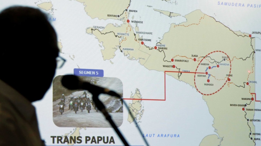 A silhouetted man stands in front of a map of the Papua region.