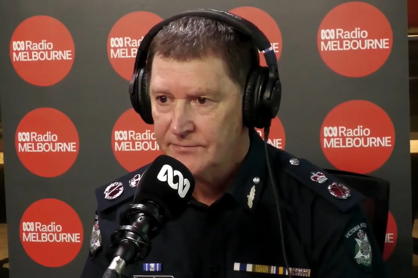 A man wearing a police uniform and headphones speaks into a microphone at ABC Radio Melbourne.