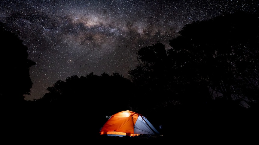 tent lit up under a starry sky