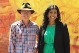 Tim Read smiles in a felt hat and checked shirt, next to Samantha Ratnam in a black jacket.