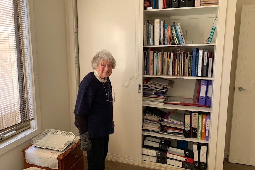 women stands in front of wardrobe with books. 