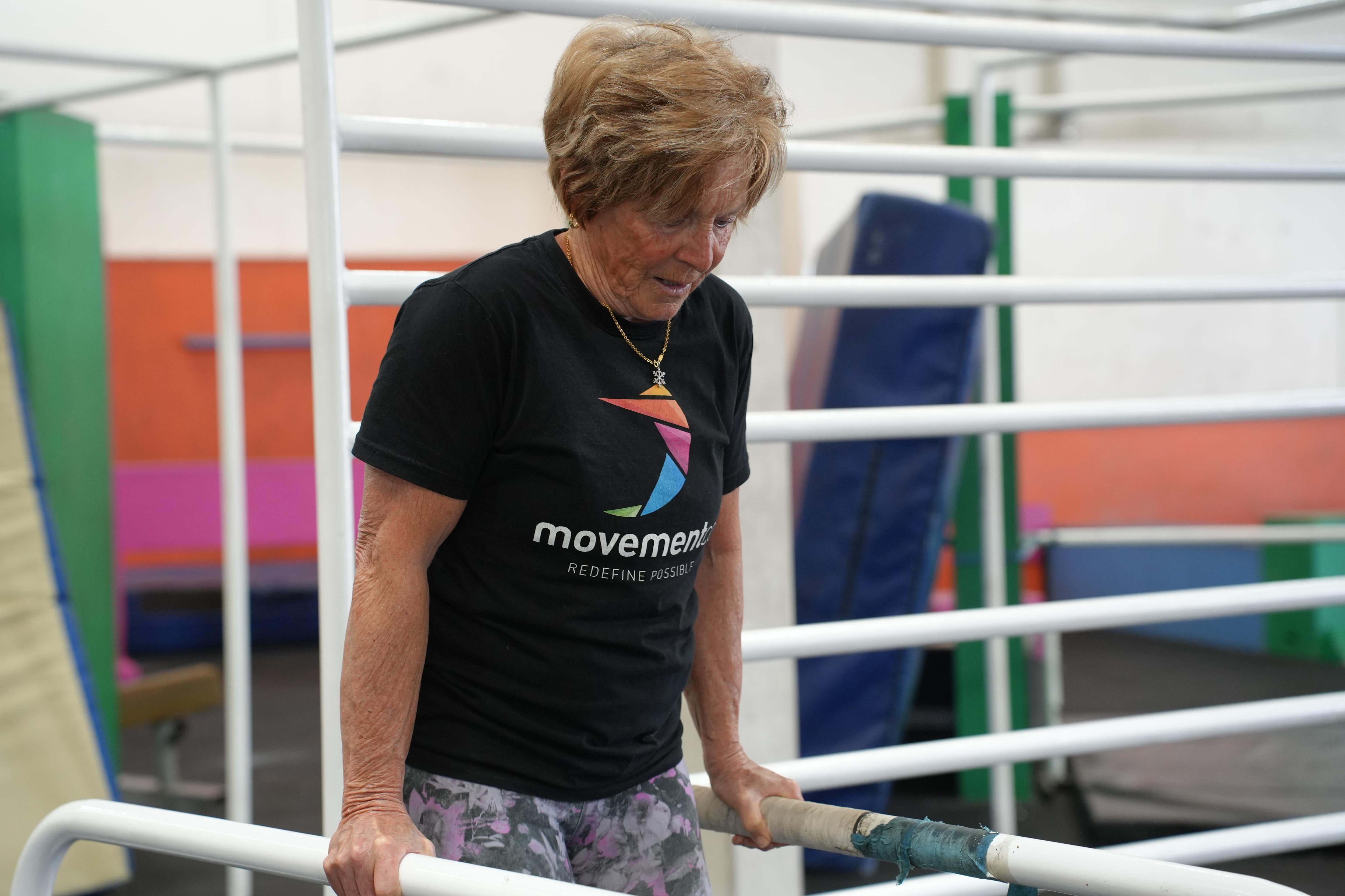 Esther holding herself up between two parallel bars 