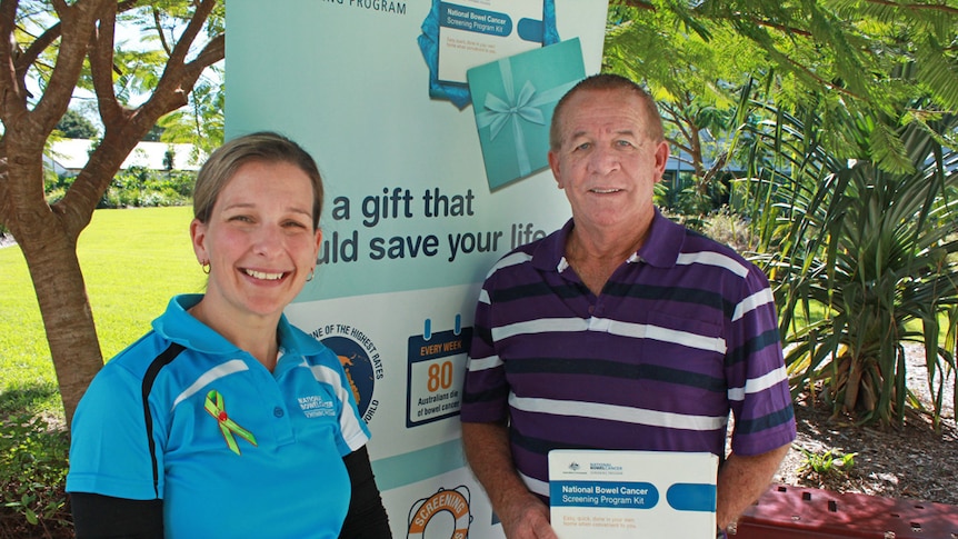 rachel and david smiling in front of a bowel cancer awareness sign at the Mackay Base Hospital