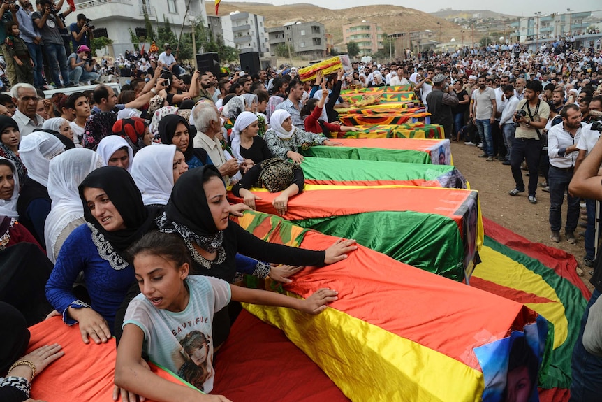 Coffins are draped in the Kurdish flag at a mass funeral for people killed during clashes between Turkish forces and PKK Kurdish militants.