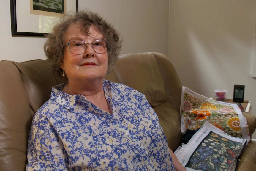 Merran Dawson sitting on a brown couch wearing a blue and white floral shirt.