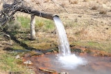 Water flowing onto the ground from a round pipe.