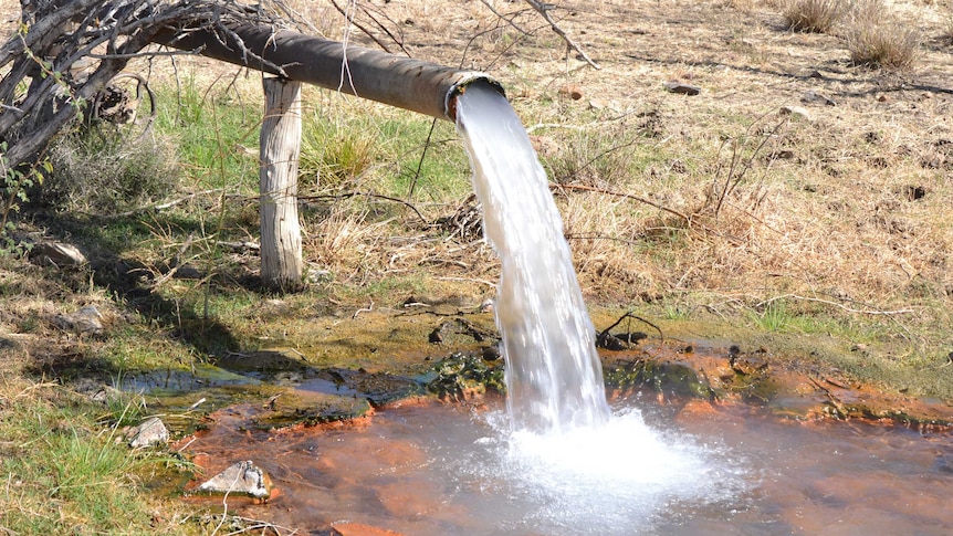 Water flowing onto the ground from a round pipe.