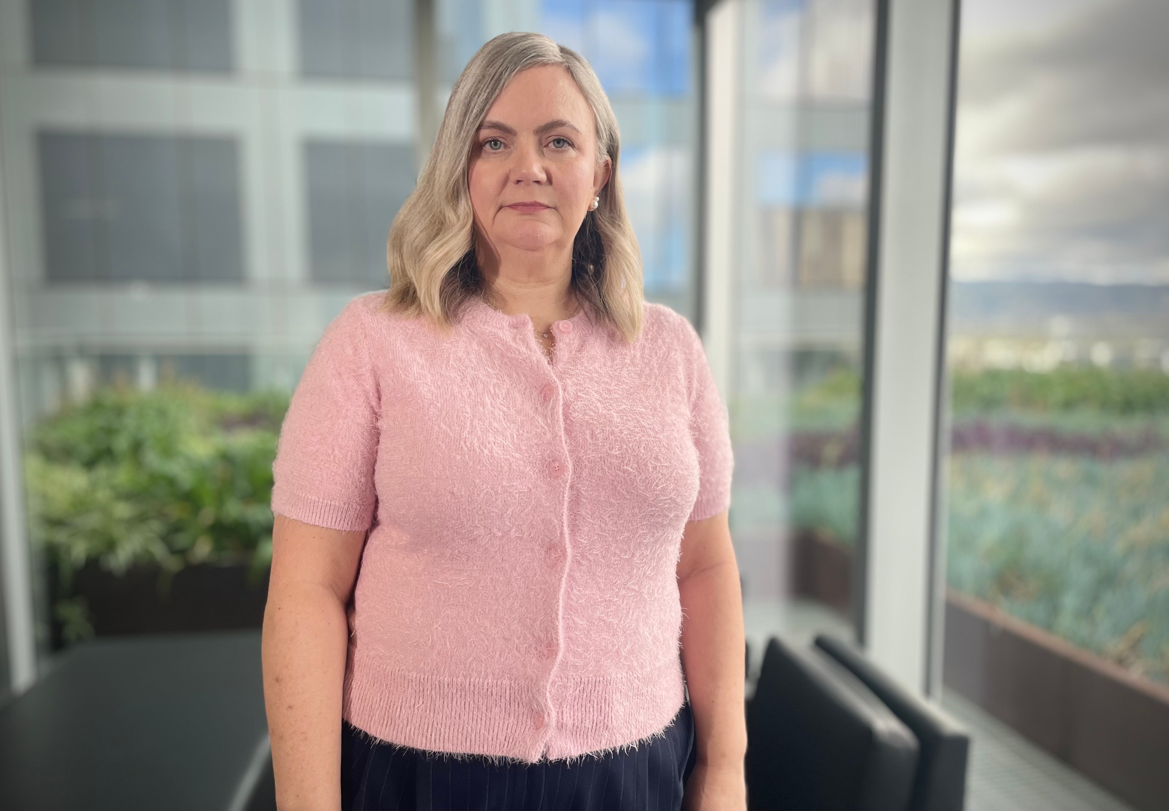 Woman in office wearing a pink shirt looks at the camera