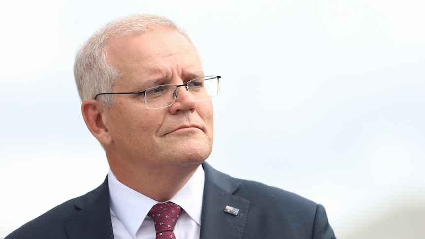 Scott Morrison wearing a dark suit and maroon tie looking off to the right