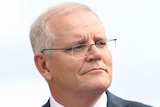 Scott Morrison wearing a dark suit and maroon tie looking off to the right
