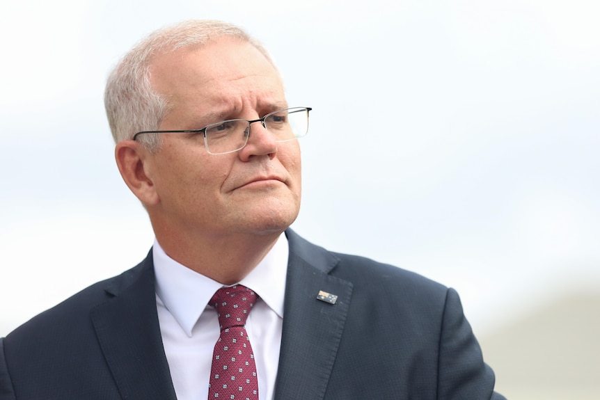 Scott Morrison wearing a dark suit and maroon tie looking off to the right