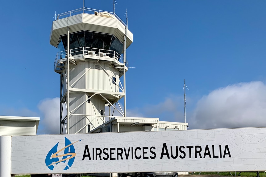 A white control tower against a blue sky in Albury, with a white sign that says air traffic services. 