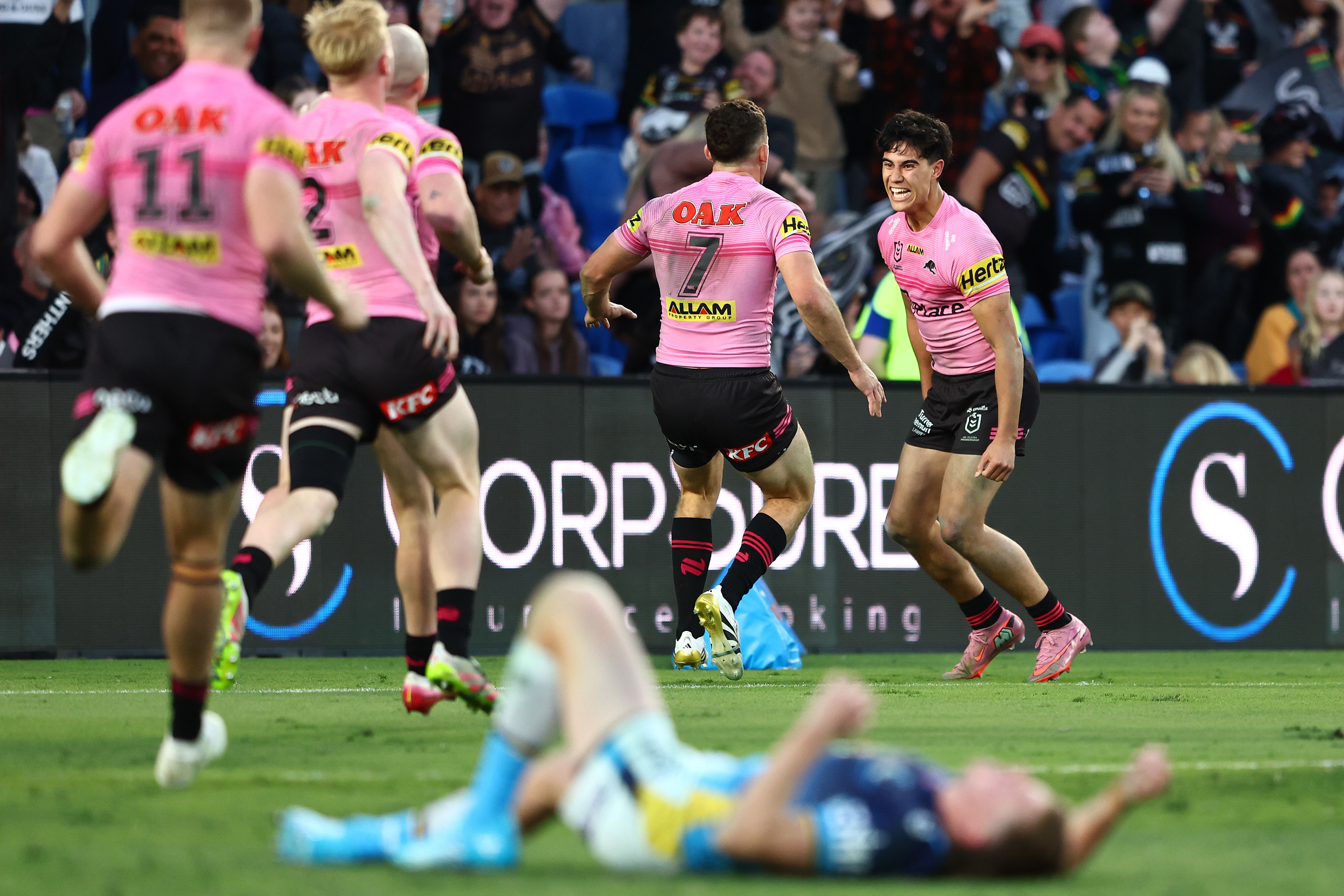 NRL players in pink celebrate and a player in blue is on the ground