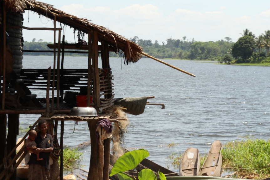 A women holds her child in front of their hut on the banks of Murry Lake